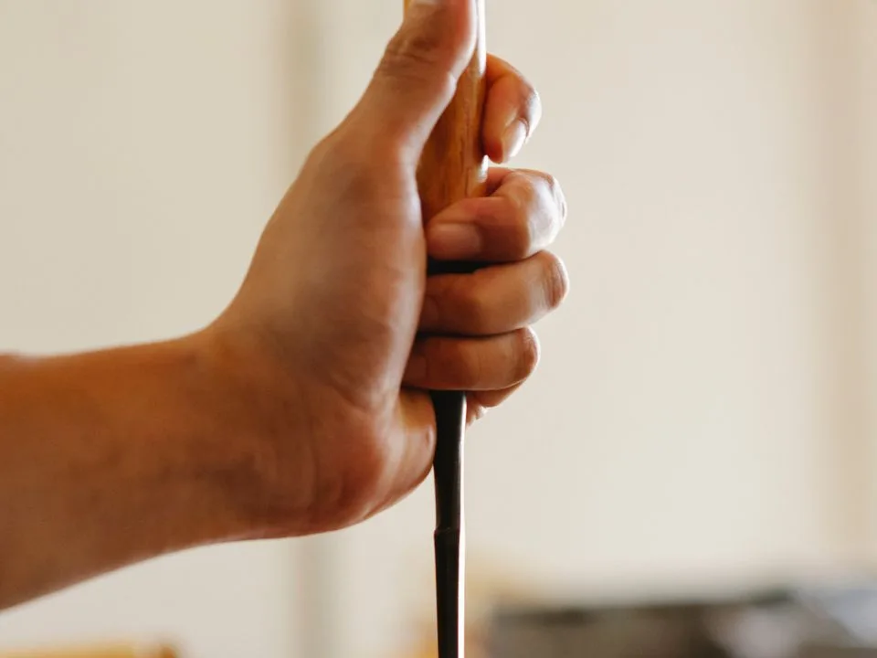 Hands of a woodworker using chisel and mallet at the bench